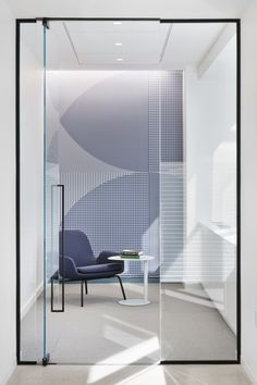 an empty room with a chair and table in front of a glass wall that has geometric designs on it