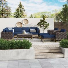 a patio with couches, chairs and plants on the side walk in front of a white wall