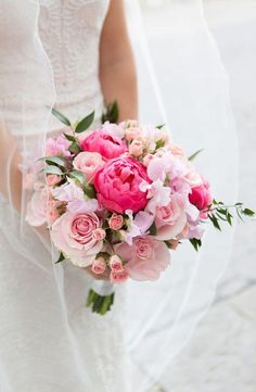 a bride holding a bouquet of pink flowers