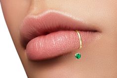 a woman's nose with a ring on top of her lip and an emerald stone in the middle