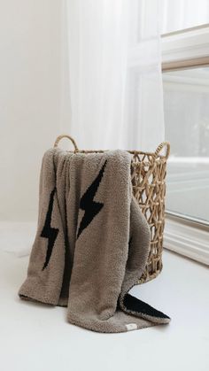 a blanket with a lightning symbol on it next to a basket in front of a window