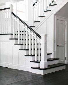 a white staircase with black railing and wood flooring