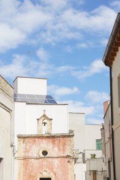 an old building with a clock on the side and a small door in front of it