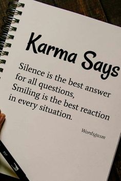 a hand holding a pen over a notebook with the words karma says on it