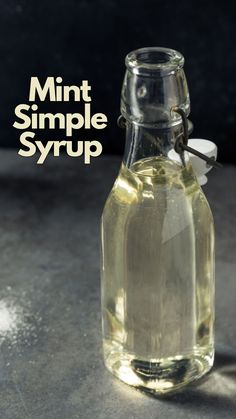 a glass bottle filled with liquid sitting on top of a cement floor next to a black wall