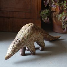 an animal figurine sitting on top of a table next to a potted plant