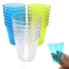 a hand is holding a plastic cup with blue and green cups in it next to each other