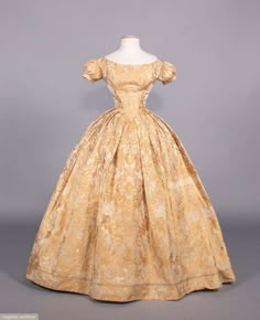 2-pc evening dress of patterned gold floral festoon motif on tan silk damask ground, bodice w/ bateau neckline, short puff sleeves, piped throughout, lined in glazed linen, CB hook & eye & decorative lacing, full box pleated skirt, c. 1840, very good. Deaccessioned by the Valentine Museum. Measurements & condition report available upon request. Two Piece Evening Dresses, 1840s Fashion, Box Pleated Skirt, Tan Silk, Silk Evening Gown, 19th Century Fashion, History Fashion, Antique Dress, Victorian Clothing