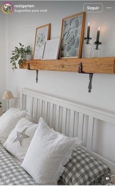 a bed with pillows and pictures on the wall above it, along with two candles