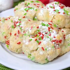 several cookies with sprinkles on a white plate next to a red and green napkin