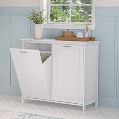 a white cabinet with an open door in a blue and white room next to a window