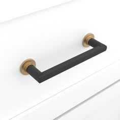 a white dresser with two brass handles and black knobs on the front door handle