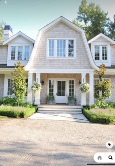 a large house with white trim and windows on the front door is surrounded by greenery