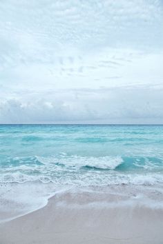 an ocean view with waves coming in to shore and the sky above it is cloudy