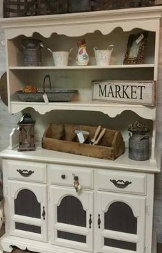 a white hutch with baskets and other items on the top shelf in front of it