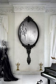 an ornate mirror hangs on the wall next to a piano in a room with white walls