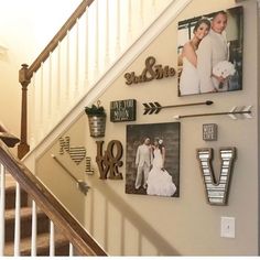 a staircase with pictures on the wall and metal letters hanging from the handrails