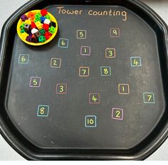 a black tray with numbers on it and a yellow bowl filled with colorful candies