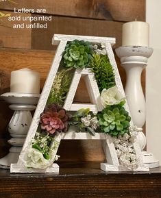 the letters are decorated with flowers and succulents on top of a table