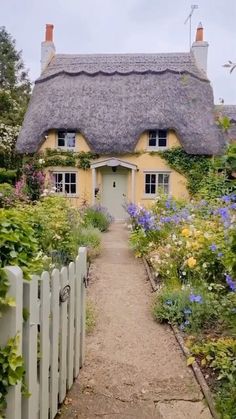 a house with a thatched roof surrounded by flowers