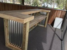 a wooden table sitting on top of a floor next to a metal fence and window