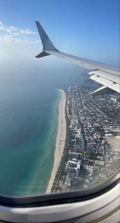 an airplane wing flying over a beach and ocean