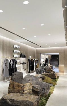 a clothing store with moss growing on the floor and rocks in front of it,