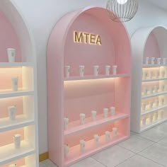 the interior of a store with pink walls and shelves filled with white cups, vases and jars