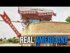 an old building with a sign that says pioneers village and the real american flag on top