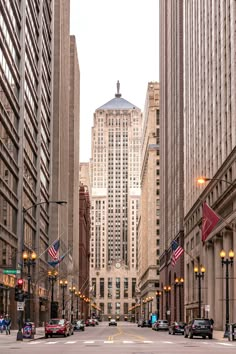 an empty city street with tall buildings and american flags on the side walk in front of it