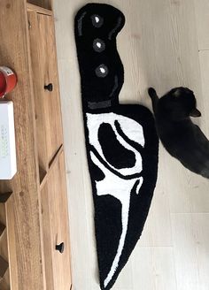 a black cat standing next to a rug on the floor