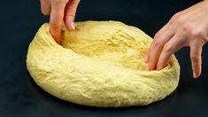 someone is kneading dough into a ball on a black surface with their hands