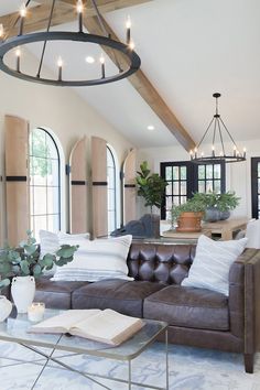 a living room filled with furniture and lots of windows next to a ceiling mounted chandelier