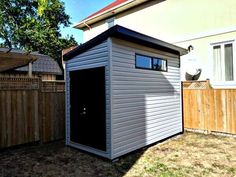 a small shed sitting next to a wooden fence