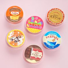 four small round tins with different types of food in them on a pink surface