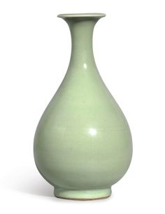 a green vase sitting on top of a white table