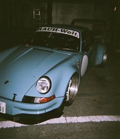 a blue sports car is parked on the side of the road at night with its hood up