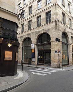 an empty street in front of a tall building with lots of windows on each side