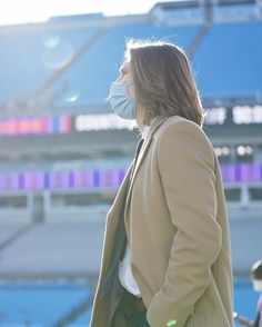 a woman wearing a face mask standing in front of a stadium