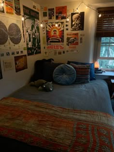 a bed room with a neatly made bed and lots of posters on the wall above it