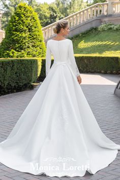 a woman wearing a white wedding dress with long sleeves