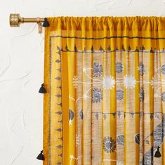 a yellow curtain with black tassels hanging from it's rodulage