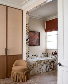 a bathroom with a tub, chair and painting on the wall