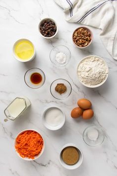 an assortment of ingredients are laid out on a marble counter top, including eggs, flour, butter, and other items