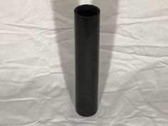 a black vase sitting on top of a white sheet