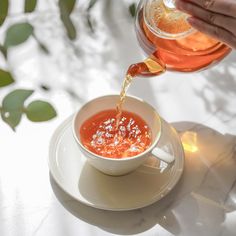 someone pouring tea into a cup on a saucer