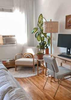 a living room filled with furniture and a computer on top of a wooden desk next to a window