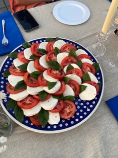 a blue plate topped with sliced tomatoes and mozzarella on top of a table