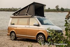 an orange van parked on top of a sandy beach next to the ocean with its door open