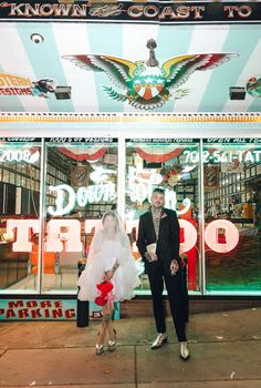 a man and woman standing in front of a carnival store with their wedding dress on